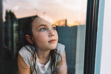 A child thoughtfully staring out of a window.
