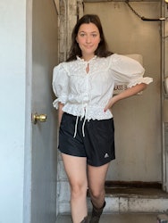 A woman wearing a white shirt top and black athletic shorts