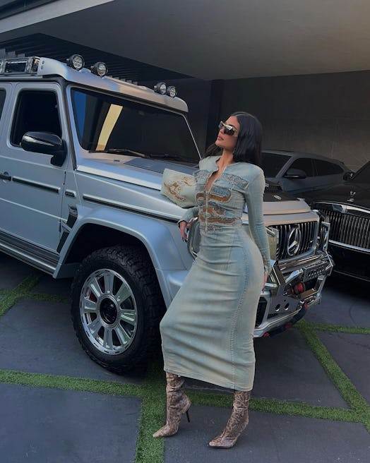 Full photograph of Kylie Jenner posing in front of a silver Mercedes-Benz G-Class in a full denim dr...