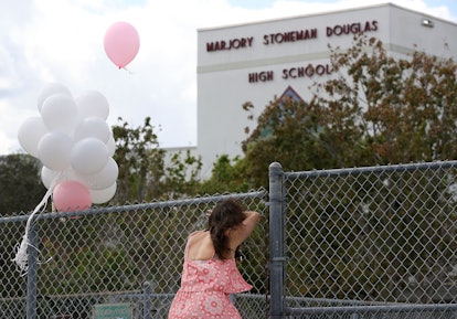 Young girl resting against the fence around the Marjory Stoneman Douglas High School
