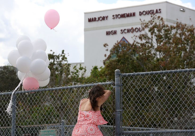 Young girl resting against the fence around the Marjory Stoneman Douglas High School