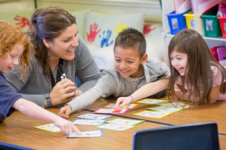 Preschoolers with their teacher learning with big cards at a table.