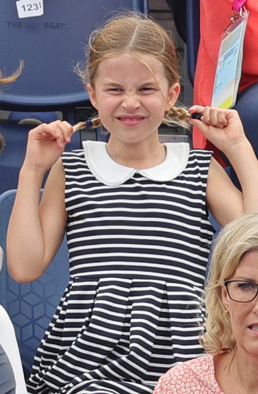 Princess Charlotte pulling on her braided pigtails and wrinkling her nose