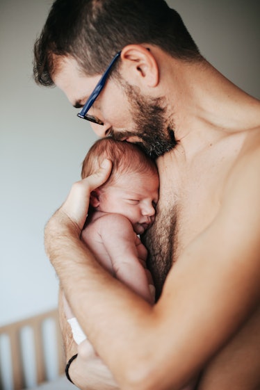 A shirtless dad holding his baby to his chest, practicing kangaroo care.