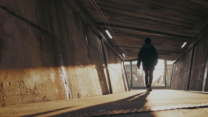 Ikumi Nakamura, seen from behind, walking through an empty tunnel.