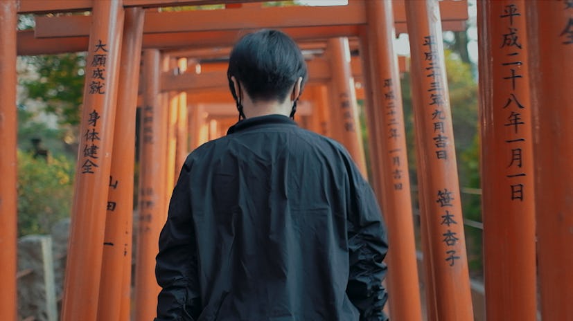 Ikumi Nakamura walking through a series of orange torii gates at a Shinto temple in Japan.