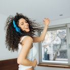 Young woman dancing on her bed about to break out into song as one of the zodiac signs most likely t...