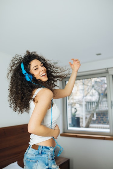 Young woman dancing on her bed about to break out into song as one of the zodiac signs most likely t...