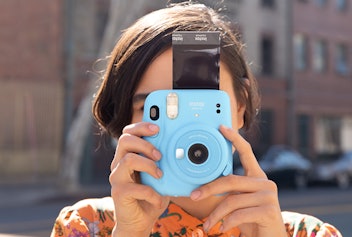 Girl holding Turquoise Fujifilm INSTAX Mini 11 camera for teens