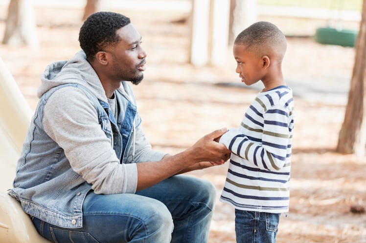 A dad holds his son's hands while gently disciplining him.