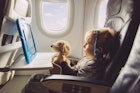 孩子在飞机上看iPad，拿着毛绒玩具