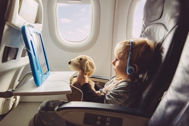 Toddler on airplane watching iPad and holding stuffed animal