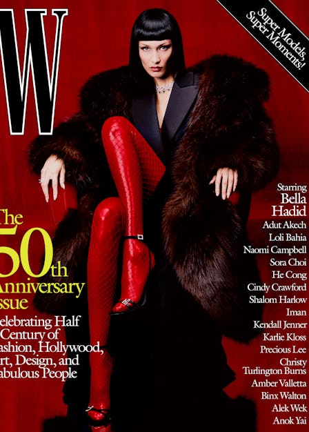 Bella Hadid in a coat, tuxedo dress, sandals, and red fishnets on the cover of W Magazine's 50th ann...
