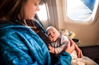 一位母亲抱着熟睡的婴儿坐飞机。