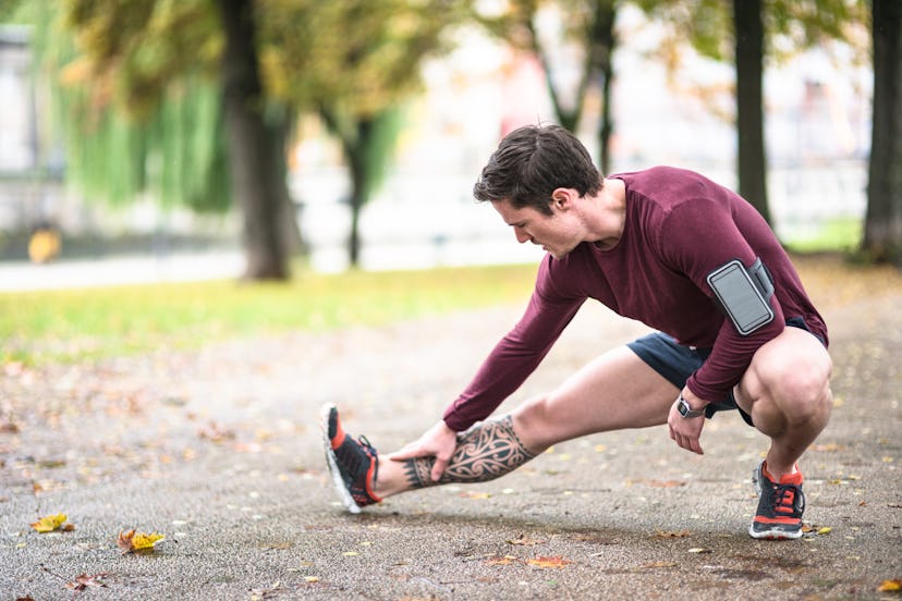 A man bending down, stretching his calf and ankle.