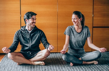 A man and woman in lotus position, laughing together.