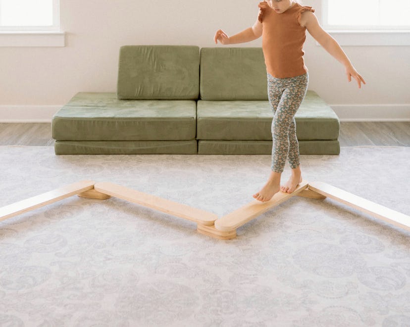 A little girl walking on a wooden climbing toy