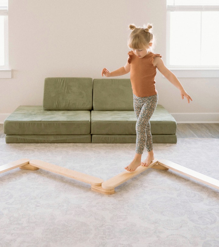 A little girl walking on a wooden climbing toy