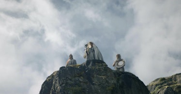 Three mysterious figures stand atop of tall ledge in The Lord of the Rings: The Rings of Power