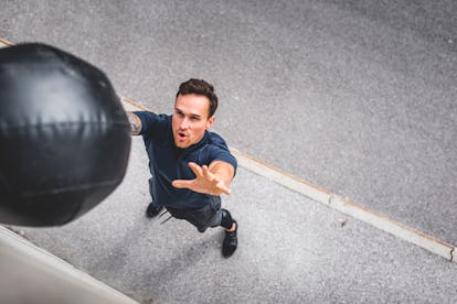 A man throwing a medicine ball at a wall.