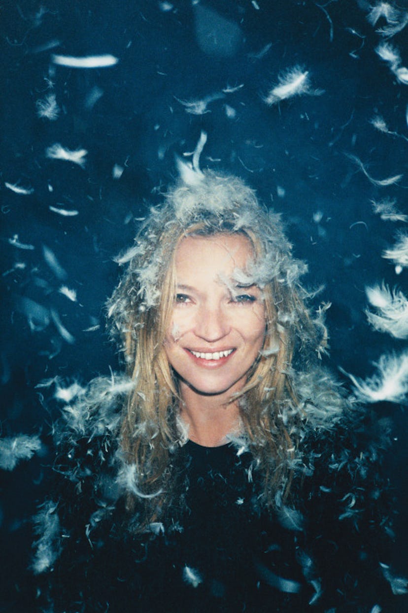 Kate Moss grinning with feathers on her head