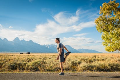 A runner grabs his foot and bends his leg to his butt while standing, stretching his quad.