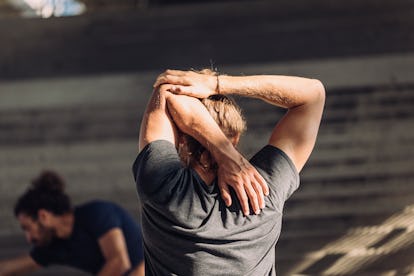 Back view of a man stretching his triceps behind his back.