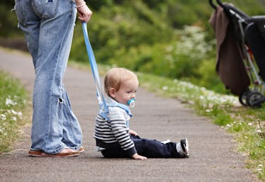 A toddler on a child leash, held by a parent.