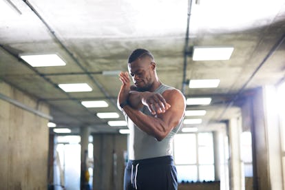 A man stretches his arm across his chest.