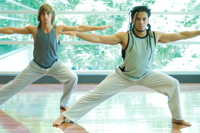 Two men do a side lunge stretch in an exercise class.