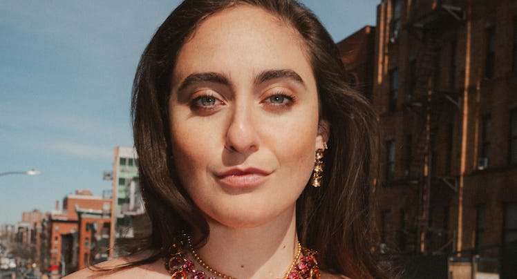 Catherine Cohen, a comedian, stares into the camera with a bemused expression. She's wearing a black...