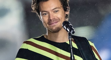 Harry Styles wearing a striped shirt and smiling while performing