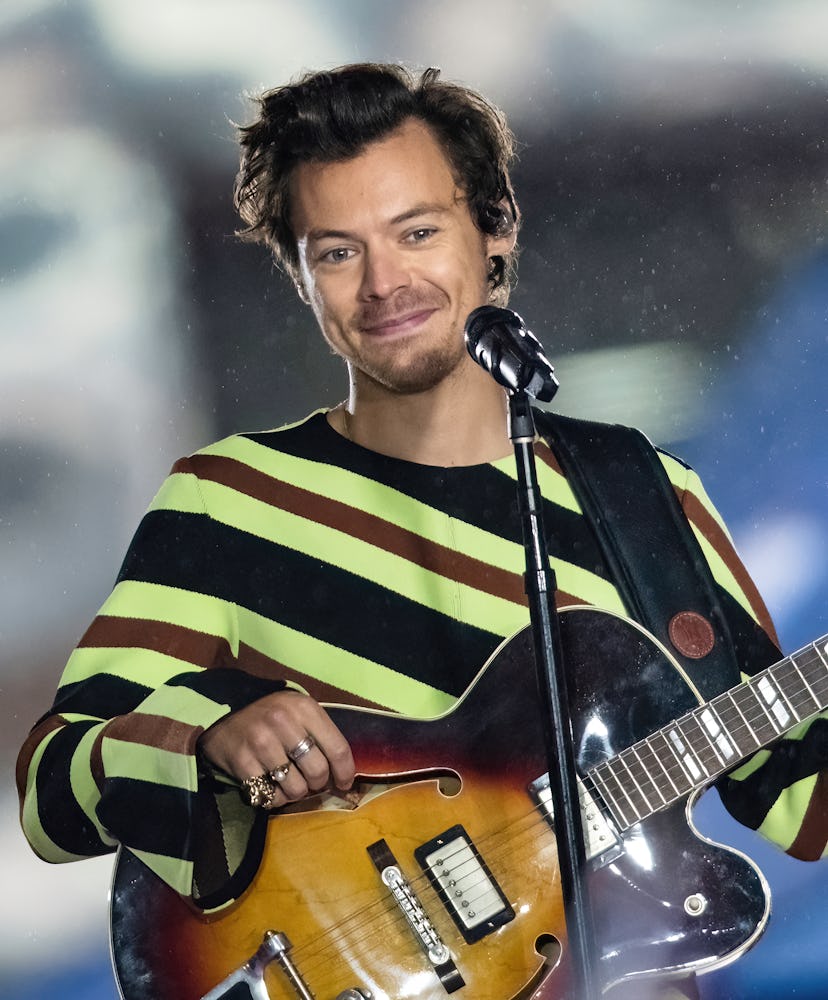 Harry Styles wearing a striped shirt and smiling while performing