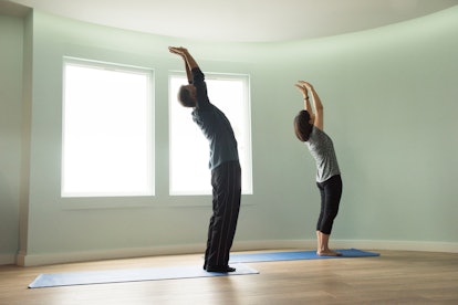 A man and woman standing and stretching their arms upward.