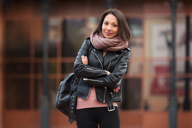A woman standing with arms crossed and wearing a jacket similar to the best leather jackets for peti...