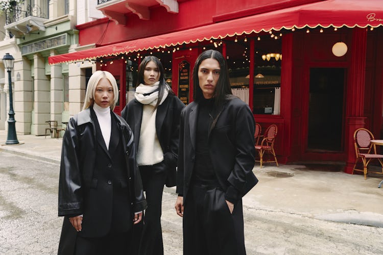 Three models: two are in black blazers and coats with white shirts, while one is in a beige sweater ...