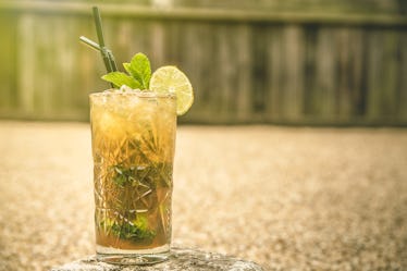 Whiskey smash cocktail with two straws sitting on table