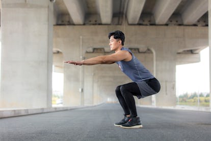 A man doing a squat with arm movements.