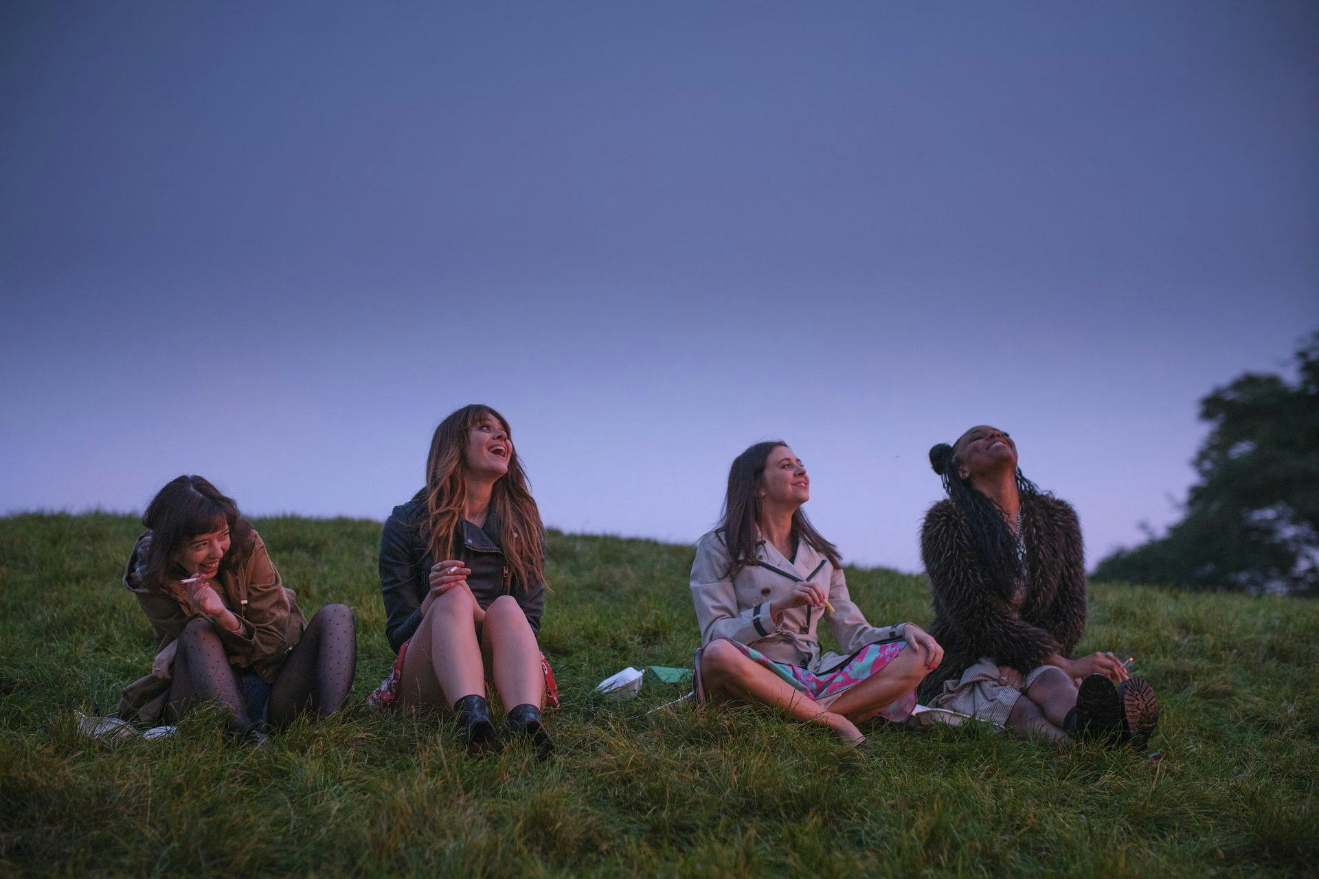 'Everything I Know About Love' cast sitting on grass.