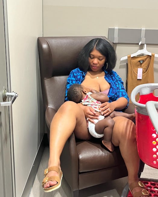 Black mother sits in a brown leather chair breastfeeding her baby in the store.