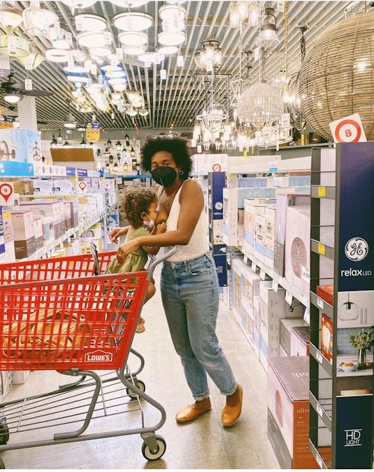 Black mother breastfeeding her black child who sits in a shopping cart in Target
