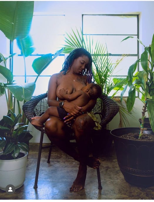 Black mother sitting in a chair with no shirt on breastfeeding her Black baby.