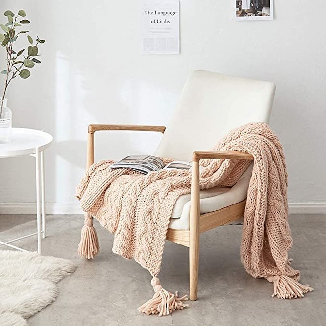 This classic cable knit blanket has stylish tassels.
