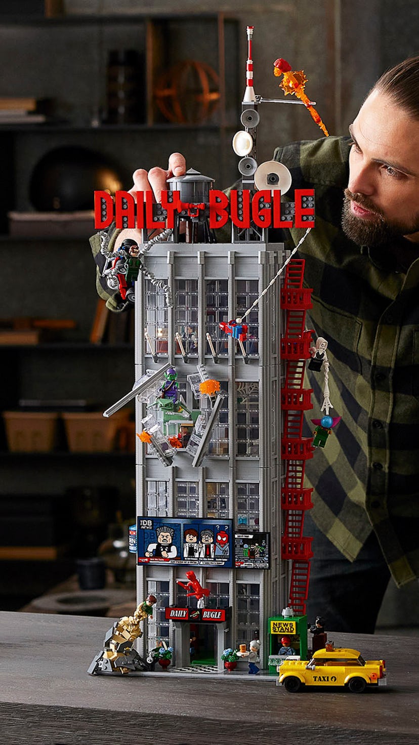 Man building and playing with the coolest minifigures from LEGO's Daily Bugle Set.