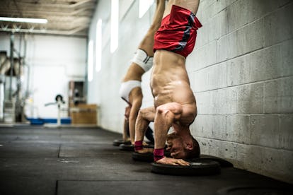 Bestes Körpergewichtstraining für Muskelaufbau 2 Ein Mann und eine Frau machen Liegestütze auf dem Handstand an einer Wand.