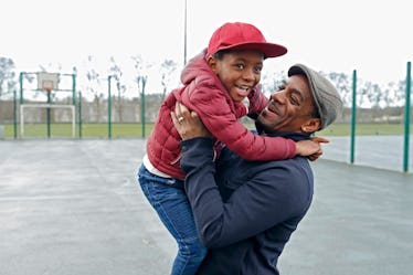 A dad holding his son up and smiling in a park.