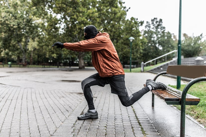 A man in outdoor workout gear doing Bavarian split squats with help of a bench