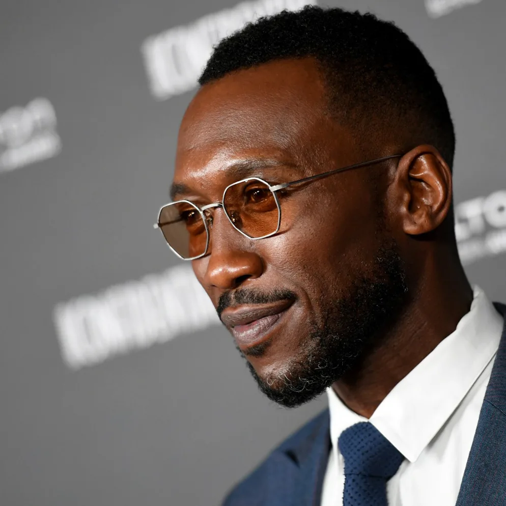Mahershala Ali wearing tinted shades and a suit at a red carpet