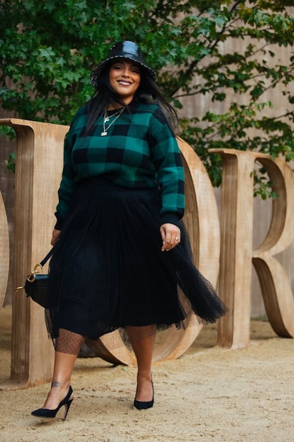 Paloma Elsesser wears a black bucket hat, green check sweater, black tulle skirt, and black heels be...