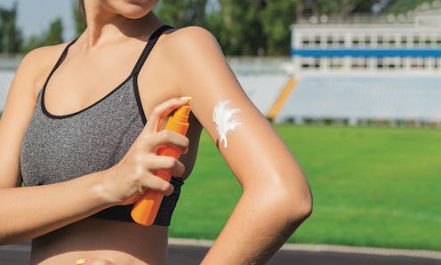 The best sunscreens for runners are must-haves, and in this photo a person in a sports bra applies a...